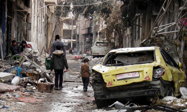 Mọi người đi bộ dọc một đường phố bị tàn phá bởi nội chiến ở Homs, Syria.
