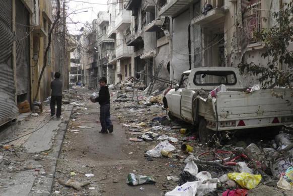 Trẻ em chơi dọc đường phố với các tòa nhà bị tàn phá bởi nội chiến ở Homs, Syria.