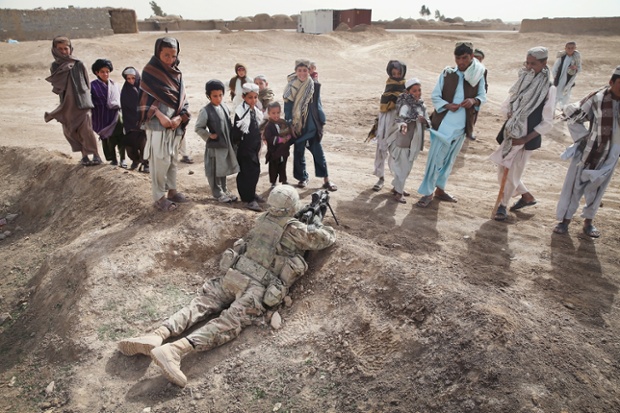 Trẻ em đứng nhìn một binh sĩ Mỹ đang giữ chốt trong khi tuần tra tại một ngôi làng gần Kandahar, Afghanistan.