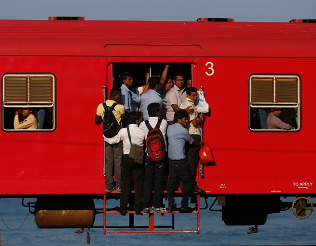 Hành khách phải đứng ở cửa trên một chuyến tàu đông người di chuyển tới thủ đô Colombo, Sri Lanka.