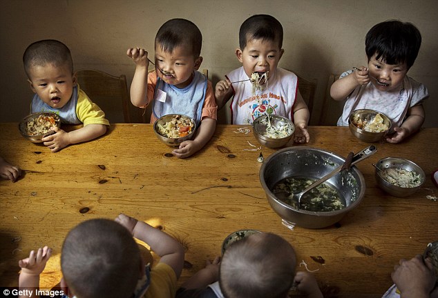 Thời gian ăn tối: trẻ em Trung Quốc trẻ mồ côi ăn một bữa ăn tại trung tâm.  Ngay cả khi Trung Quốc bắt đầu để thư giãn các chính sách một con, cho phép hàng triệu gia đình có một đứa con thứ hai, nó vẫn còn gây bất lợi cho những người coi thường các quy tắc