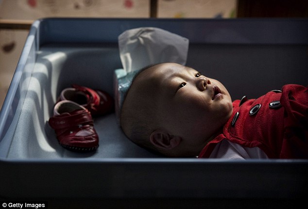 Tương lai không chắc chắn: Một cô gái trẻ mồ côi Trung Quốc đặt trên bàn thay đổi ở trung tâm Bắc Kinh