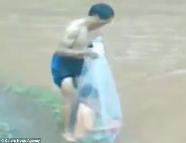 Đóng gói: Khi sông địa phương bị ngập lụt, ngăn chặn trẻ em từ khi đến trường, một phụ huynh đã đưa họ qua trong một túi nhựa