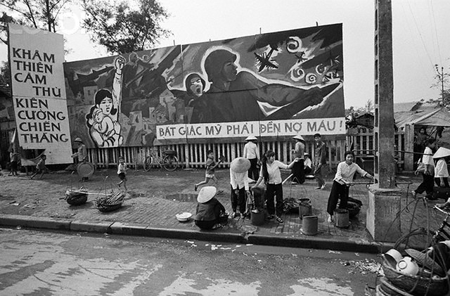 HANOI: Children run and play in front of a huge anti-American mural in a downtown Hanoi street March 29, the day when the last U.S. POWs were released. Banner across bottom of mural reads, make the American aggressors pay in blood. --- Image by © Bettmann/CORBIS