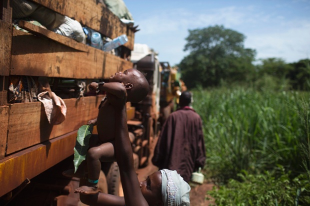 Một phụ nữ đưa con nhỏ lên một chiếc xe tải để sơ tán khỏi tình trạng bạo lực ở Bangui, Trung Phi.