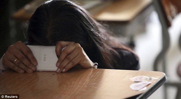Chờ đợi: Một phụ nữ cầu nguyện đằng sau điện thoại di động của mình tại trường trung học Danwon ở Ansan.  Các thành viên gia đình của những người mất tích cho các tin nhắn gửi đến những người bị mắc kẹt bên trong, yên tâm họ giúp đỡ là trên đường