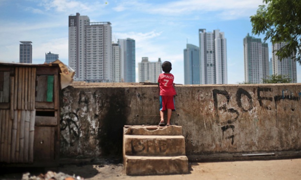 Một cậu bé ngắm những tòa nhà chọc trời từ một khu ổ chuột ở Jakarta, Indonesia.