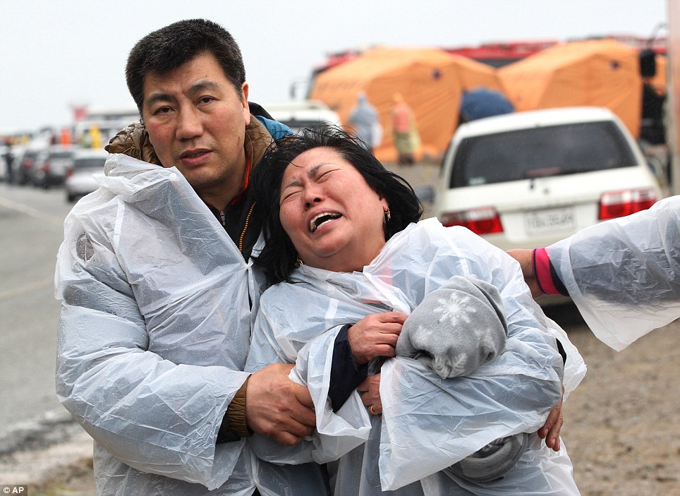 Thoải mái: Một người đàn ông an ủi một người phụ nữ trên đảo Jindo.  Gia đình đã bị bỏ lại thất vọng trong khi mưa và mạnh mẽ dòng đã cản trở những nỗ lực tìm kiếm
