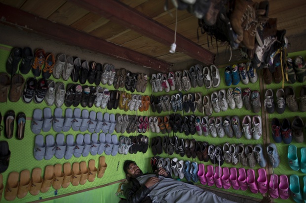 Một chủ cửa hàng bán giày dép tranh thủ ngủ trong chờ khách hàng ở Kabul, Afghanistan.