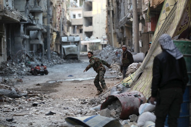 Một chiến binh phiến quân ném dây để kéo màn che khỏi các binh sĩ bắn tỉa của quân đội chính phủ Deir al-Zor, Syria.