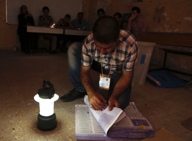 Nhân viên bầu cử kiểm phiếu bằng ánh đèn dầu do mất điện khi các điểm bỏ phiếu đóng cửa ở Baghdad, Iraq.