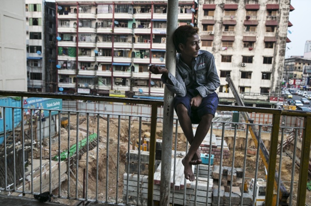 Nam thanh niên ngồi cạnh một công trường xây dựng ở Rangoon, Myanmar.