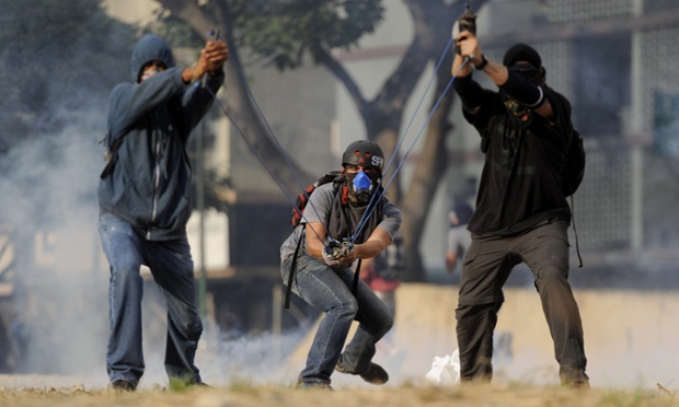 Những người biểu tình chống chính phủ sử dụng súng cao su bắn đá vào cảnh sát ở Caracas, Venezuela.