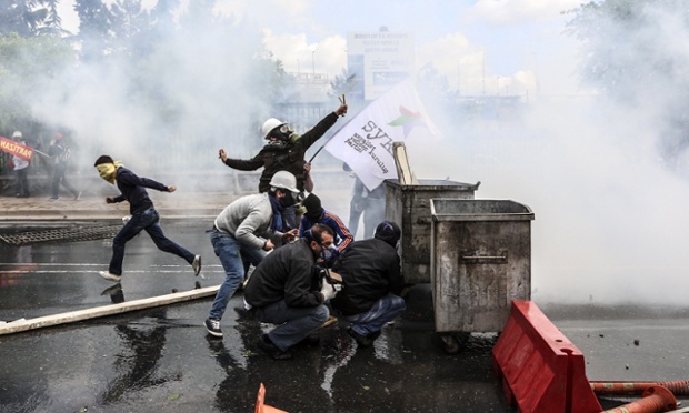 Những người biểu tình trú sau thùng rác khi cảnh sát chống bạo động bắn đạn hơi cay giải tán người biểu tình gần quảng trường Taksim ở Istanbul, Thổ Nhĩ Kỳ.