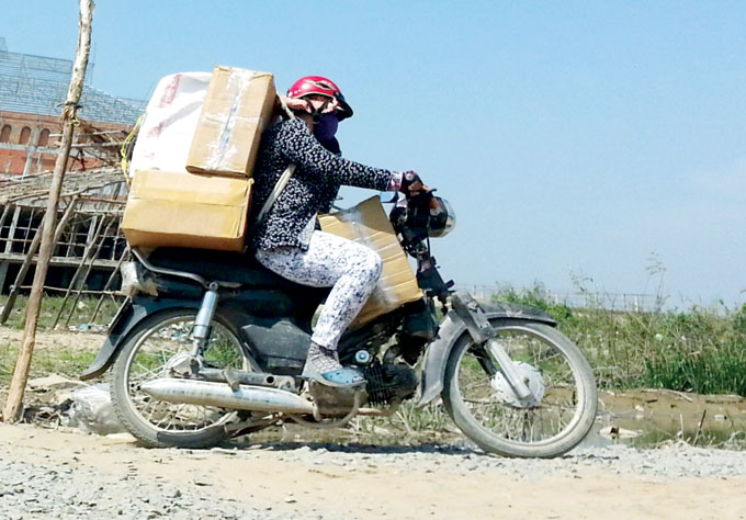 Một nữ xe thồ chở hàng lậu băng ven đồng lúa qua ấp Vĩnh Chánh 1, Châu Đốc