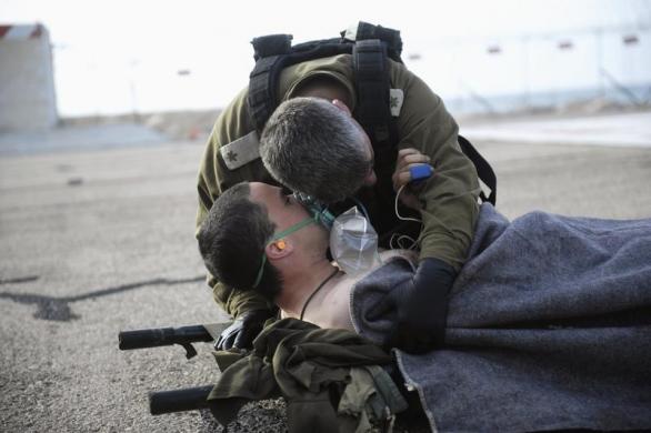 Một binh sĩ Israel lắng nghe đồng đội bị thương trong một vụ đánh bom ở thành phố Haifa.