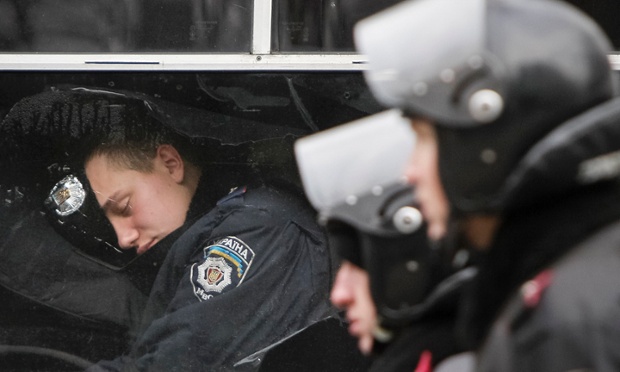 Một nhân viên an ninh ngủ trong xe bus trong khi các đồng nghiệp khác bảo vệ tòa nhà quốc hội ở Kiev, Ukraine.