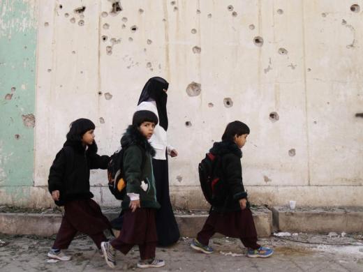 Các bé gái đi qua hiện trường một vụ đánh bom ở Sanaa, Yemen.