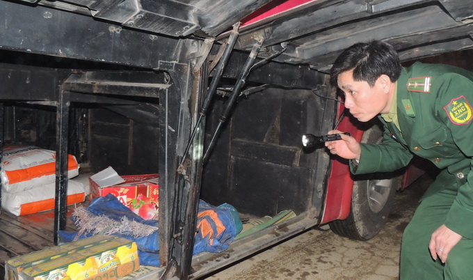 Một chiến sĩ biên phòng Hà Tĩnh kiểm tra xe khách qua cửa khẩu vào ban đêm để tránh tình trạng một số đối tượng lợi dụng trà trộn hàng hóa lậu, ma túy - Ảnh: V.Định