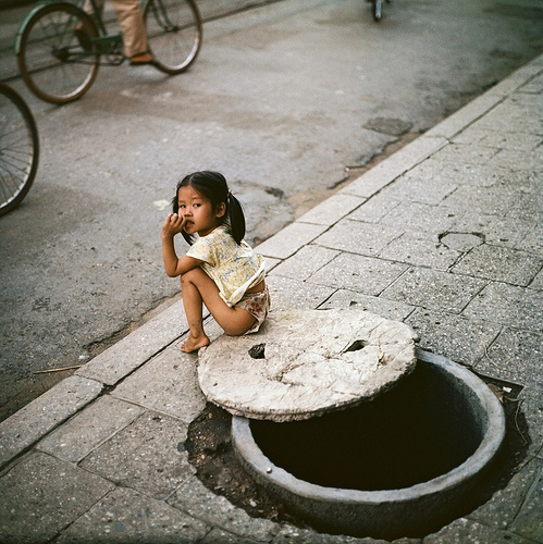 Cô bé không dám chơi quá xa hầm trú ẩn.