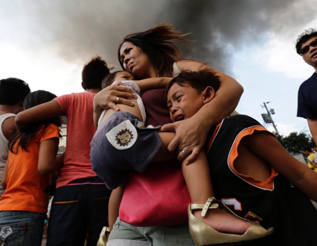 Một bà mẹ đưa con sơ tán khỏi ngôi nhà của họ bị hỏa hoạn tại một khu ổ chuột ở Manila, Philippines.