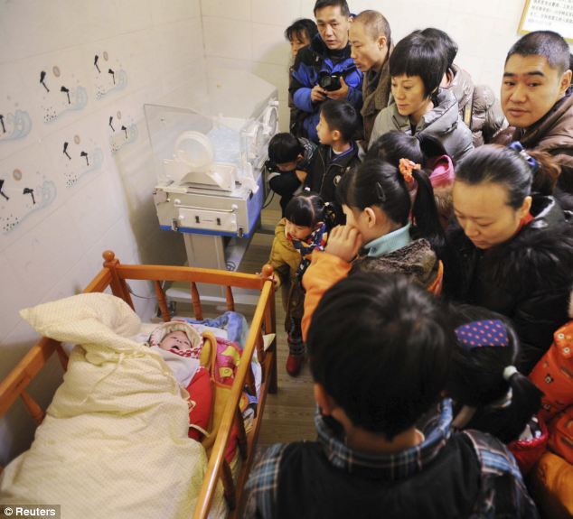 Cư dân thăm một em bé bị bỏ rơi nằm trong giường cũi tại nở em bé trong Quý Dương, tỉnh Quý Châu