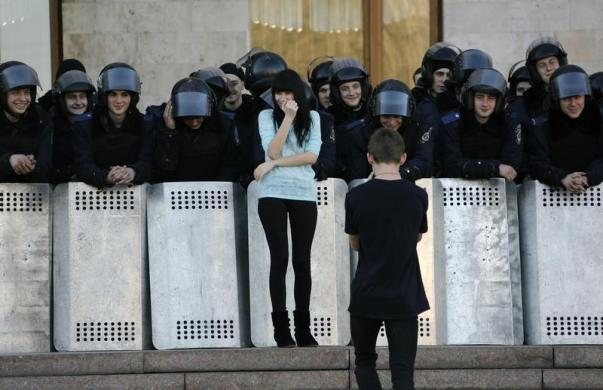 Nam thanh niên chụp ảnh bạn gái đứng cạnh cảnh sát chống bạo động Ukraine đang bảo vệ tòa nhà hành chính khỏi những người biểu tình ủng hộ Nga ở Donetsk.