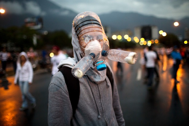 Người biểu tình đeo mặt nạ phòng khí độc được làm từ chai nhựa khi diễu hành trên đường phố ở Caracas, Venezuela.