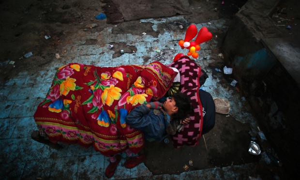 Một người đàn ông vô gia cư và vợ ngủ trên một chiếc giường thuê tại một khu dân cư nghèo ở New Delhi, Ấn Độ.