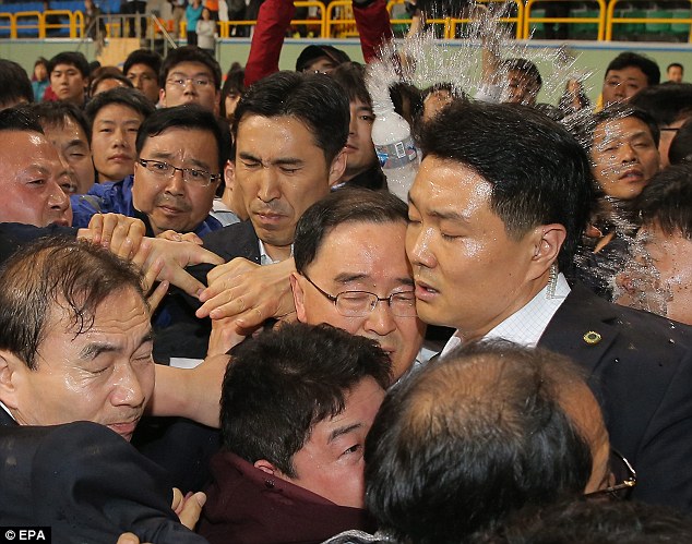 Tức giận: Thủ tướng Hàn Quốc Chung Hong-won (trung tâm) được trúng một chai nước ném bởi một thành viên gia đình thất vọng của một hành khách mất tích