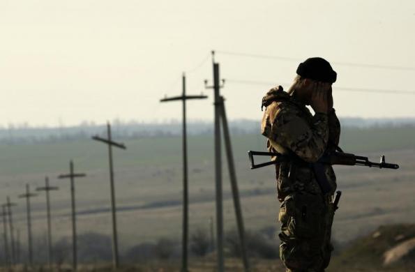 Một binh sĩ Ukraine đứng bảo vệ bên ngoài một doanh trại quân đội được dựng trên cánh đồng gần biên giới với Nga.