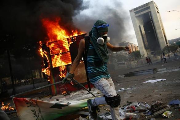 Người biểu tình chống chính phủ lập rào chắn cạnh buồng điện thoại bị đốt cháy tại quảng trường Altamira ở Caracas, Venezuela.