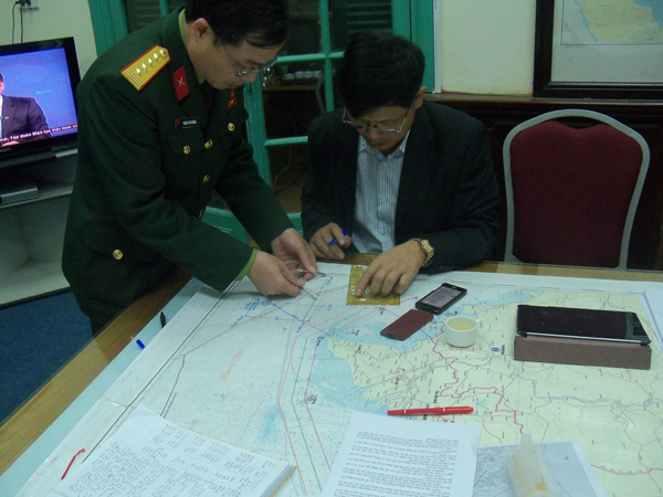 Ông Vũ Thế Chiến (áo đen), Phó Chánh Ủy ban Quốc gia tìm kiếm cứu nạn, đang phân tích vị trí chiếc máy bay mất tích.