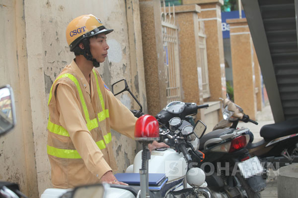 Trung úy Khanh nhìn thấy chiếc ví màu đen của một người đánh rơi gần chốt làm việc. Anh đã nhanh chóng bước ra nhặt lại trước sự chứng kiến của đồng đội và người dân đi đường.