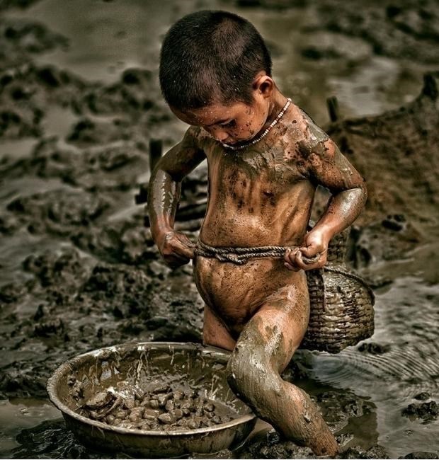 Em bé trần truồng vùi mình trong bùn nhớp nháp để nhặt cá, cua, ốc kiếm sống qua ngày.