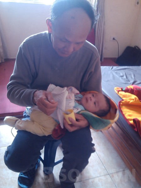 Ông Hồ Bính (bố chồng chị Dung) cho bé Hồ Sỹ Hoàng Hải uống sữa