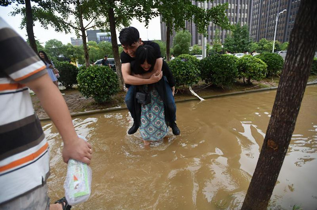 Sợ người yêu bị ướt giày, cô gái trẻ kiên quyết lội nước cõng chàng trai qua đường - Ảnh 2.