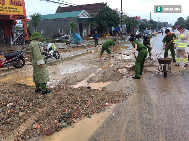 Hà Tĩnh: Công an xắn quần, đội mưa dọn đất đá vương vãi trên đường - Ảnh 1.