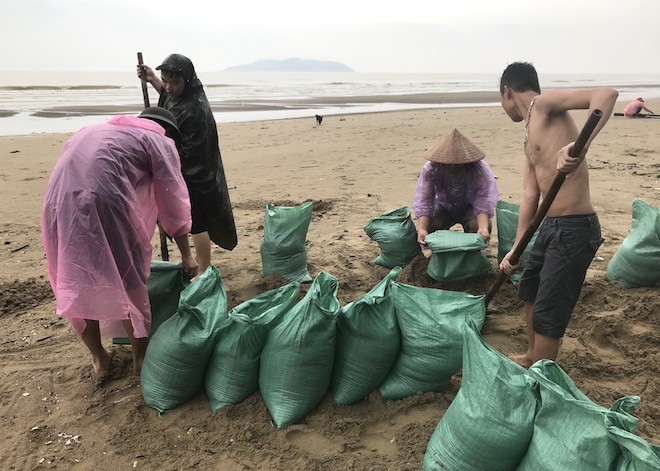 Tin bão số 3 sắp đổ bộ: Nhiều thanh niên ra bờ biển xúc cát để chuẩn bị chằng chống nhà cửa.