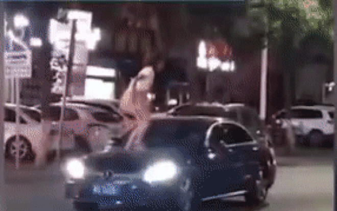 Người phụ nữ trèo lên nóc xe ô tô đập phá, lột đồ gây sốc, tài xế bất lực chỉ biết đứng nhìn - Ảnh 2.