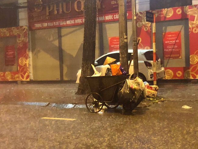 Chạnh lòng với hình ảnh cô lao công dọn rác bên lề đường trong đêm 30 Tết mưa bão - Ảnh 2.