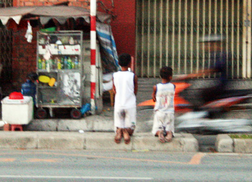 Hai bé trai bị bắt quỳ trên dải phân cách ở Đại lộ Đông Tây. Ảnh: An Nhơn