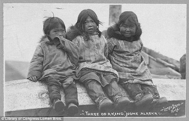 Children of the Arctic: Three Eskimo children are seen seated side by side, their hoods removed to reveal smiles and playful eyes despite the cold climate otherwise adapted to by the locals