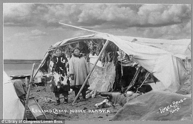 Alaskan camp: Photographed around 1916, two women are seen around a camp with furs and skins seen hanging inside