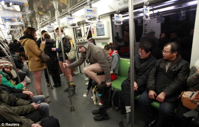 Surprise: Passengers on a Shanghai train look startled as one passenger, complete with warm jumper and wooly hat takes off his shoes and trousers 