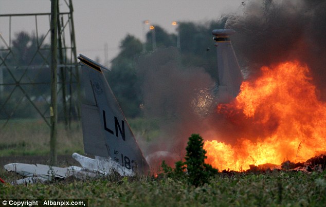 Putting out the blaze: Police said the pilot suffered minor injuries and left the scene in a helicopter