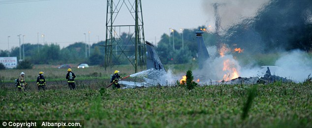 Putting out the blaze: Police said the pilot suffered minor injuries and left the scene in a helicopter