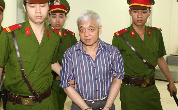 Bầu Kiên (áo kẻ) bị dẫn giải về nhà giam sau khi Hội đồng xét xử công bố hoãn phiên tòa ngày 16/4/2014 (Ảnh:  Baodautu.vn)