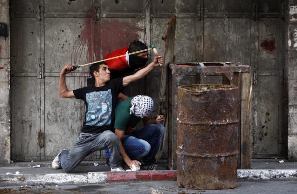 Một người biểu tình Palestine sử dụng súng cao su bắn đá vào quân đội Israel tại thành phố Hebron, Bờ Tây.
