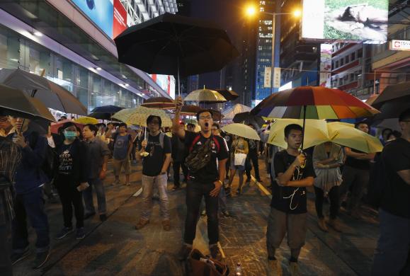 Người biểu tình cầm ô, hô khẩu hiệu tại khu phố thương mại Mongkok, Hong Kong.